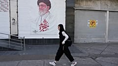 امرأة تمر أمام ملصق للمرشد الأعلى الإيراني الراحل آية الله علي خامنئي في وسط مدينة طهران، إيران