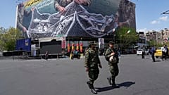 Zwei Polizisten gehen vor einem Anti-US-Plakat, auf dem US-Flugzeuge in das Fischernetz der iranischen Streitkräfte auf dem Eqelab-e-Eslami in Teheran fliegen, 5. April 2026