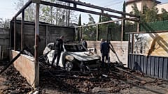 فلسطينيون يتفقدون سيارة محترقة إثر هجوم مستوطنين إسرائيليين على قرى قريبة في منطقة نابلس