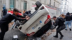 DATEI - Demonstranten kippen ein Auto während einer Demonstration gegen die Schießerei im kurdischen Kulturzentrum in Paris um, 24. Dezember 2022.