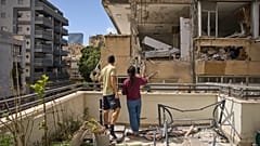 زوجان يفحصان الأضرار التي لحقت بمبنى سكني مجاور بعد أن أصيب بصاروخ إيراني في رمات غان، إسرائيل،