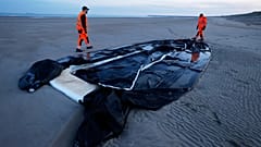 ILLUSTRATION - Des employés municipaux marchent à côté d'un canot pneumatique percé par la police et utilisé par des migrants pour traverser la Manche
