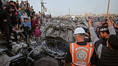 فلسطينيون يتفقدون سيارة تعرضت لغارة جوية إسرائيلية في مخيم المغازي للاجئين وسط قطاع غزة