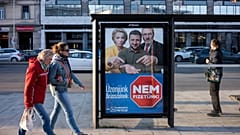 Menschen gehen neben einem Wahlplakat mit der Aufschrift "Unsere Botschaft an Brüssel: Wir werden nicht zahlen" in Budapest, Ungarn, am Samstag, den 14. März 2026, im Vorfeld der Parlamentswahlen am 12. April