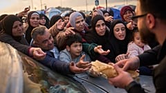 عائلات نازحة تمد أيديها في انتظار التبرعات الغذائية بجانب الخيام التي تستخدمها كملاجئ بعد فرارها من القصف الإسرائيلي في جنوب لبنان�� في بيروت،