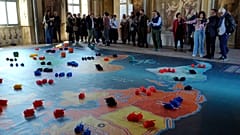 Menschen versammeln sich um eine überdimensionale Version des Brettspiels Risiko.