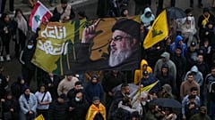 أحد أنصار حزب الله يلوح بعلم عليه صورة زعيم حزب الله الراحل السيد حسن نصر الله خلال احتجاج على رئيس الوزراء اللبناني نواف سلام.