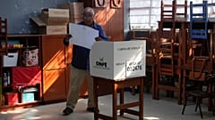 Um eleitor olha para um boletim de voto antes de marcar os seus candidatos durante as eleições gerais em Lima, Peru, no domingo, 12 de abril de 2026