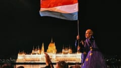  Egy európai uniós zászlóba burkolózott férfi lenget egy magyar zászlót a parlament épületével a háttérben 2026. április 13-án, hétfőn kora este, amikor az emberek Magyar Péter leváltását ünneplik. 