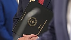 مدير وكالة المخابرات المركزية جون راتكليف يحمل حقيبة جلدية بينما يتحدث الرئيس دونالد ترامب مع الصحفيين في غرفة جيمس برادي للصحافة بالبيت الأبيض، يوم الاثنين 6 أبريل/نيسان 2026