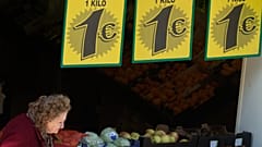Una clienta sale de una frutería con ofertas especiales de manzanas, judías verdes y calabacines, todo por un euro, en Madrid, el 20 de marzo de 2013.