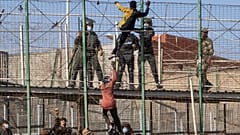 DATEI - Migranten klettern auf den Zaun, der die spanische Enklave Melilla von Marokko trennt, in Melilla, Spanien, Freitag, 24. Juni 2022.
