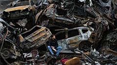 شاب يجلس قرب سيارات محترقة وحطام في موقع مبنى دُمّر جراء غارة جوية إسرائيلية يوم الأربعاء السابق، في وسط بيروت، لبنان، يوم الثلاثاء 14 أبريل/نيسان 2026.