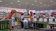In this July 15, 2019, photo, workers wrap glass fiber rolls next to the robot arms at a factory in Jiujiang in central China's Jiangxi province. July 31, 2019.