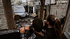 يتفقد أطفال الأضرار بعد يوم واحد من غارة إسرائيلية على مخيم الشاطئ للاجئين.