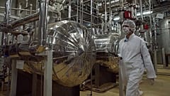Сотрудник иранской службы безопасности в защитной одежде проходит по территории завода по переработке урана недалеко от города Исфахан, 30 марта 2005 г.