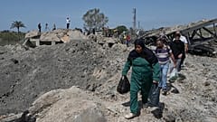 Pessoas atravessam a pé uma cratera na sequência de um ataque aéreo israelita que destruiu a ponte de Qasmiyeh, perto da cidade costeira de Tiro, 16 de abril de 2026