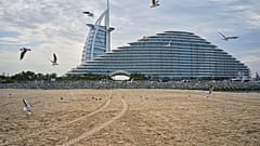 تحلّق طيور النورس فوق الشاطئ مع فندقي برج العرب وجميرا مرسى العرب في الخلفية في دبي، الإمارات العربية المتحدة، الخميس 12 مارس 2026. (صورة من وكالة أسوشيتد برس/ فاطمة شبير)