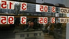 A man checks the local currency exchange rate to the US dollar and the euro in Warsaw, 24 October, 2008