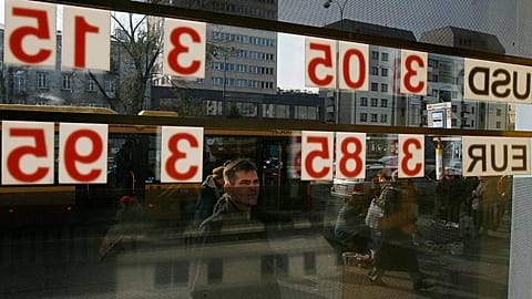 A man checks the local currency exchange rate to the US dollar and the euro in Warsaw, 24 October, 2008