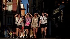 Eine Gruppe von Menschen schützt sich bei einem Spaziergang in Madrid vor der Sonne.