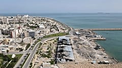 Με φόντο τα πλοία στα Στενά του Ορμούζ, ζημιές που προκλήθηκαν από αεροπορικές επιδρομές σε προβλήτα στο λιμάνι του νησιού Qeshm, 13 Απριλίου 2026
