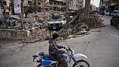رجل يقود سيارته أمام موقع مبنى دمر في غارة جوية إسرائيلية، في جنوب لبنان