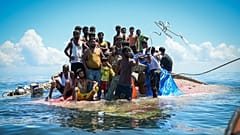 Rohingya-Flüchtlinge stehen auf ihrem gekenterten Boot, während Retter ihnen vor West-Aceh ein Seil zuwerfen, 21. März, 2024
