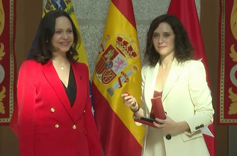 La presidenta de la Comunidad Madrid, Isabel Díaz Ayuso, de blanco, entrega la Medalla Oro a María Corina Machado, en la Real Casa de Correos, Madrid, el 18 de abril de 2026.