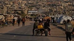 فلسطينيون يسيرون على طول شارع محاط بمبانٍ دمرتها العمليات الجوية والبرية الإسرائيلية في خان يونس، جنوب قطاع غزة، الخميس 9 أبريل 2026. (تصوير: أ.ب / عبد الكريم حنا)
