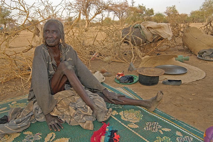 Una mujer mayor que huye de los combates en Darfur en un refugio hecho de matorrales espinosos. Frontera entre Chad y Sudán, 2004