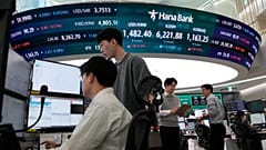 Devizakereskedők dolgoznak egy kijelzőnél, amely a Korea Composite Stock Price Indexet (KOSPI) és az amerikai dollár és a dél-koreai von közötti árfolyamot mutatja.