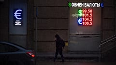 FILE: A pedestrian walks down a street near an exchange office sign displaying the currency rates for the Russian ruble, US dollar and euro in Moscow, 20 November 2024