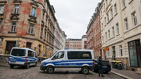 Police vehicles and officers stand during searches in the Connewitz district of Leipzig, 26 January, 2022
