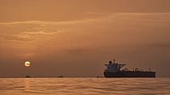 The sun rises behind tankers anchored in the Strait of Hormuz off the coast of Qeshm Island, 18 April, 2026