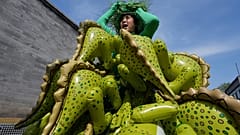 Chinese artiste Kong Ning wears a costume assembled with dinosaur balloons to commemorate Earth Day in Beijing, Wednesday, April 22, 2026.