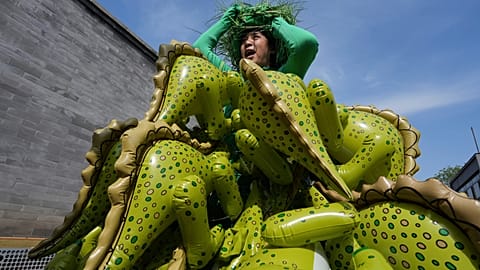 Chinese artiste Kong Ning wears a costume assembled with dinosaur balloons to commemorate Earth Day in Beijing, Wednesday, April 22, 2026.