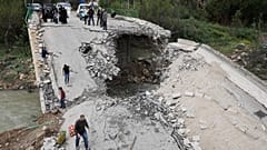 Yerlerinden edilen insanlar, Hizbullah ile İsrail arasındaki ateşkesin ardından köylerine dönerken yıkılmış bir köprüden geçiyor.