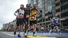 Boston Marathon runners Robson De Oliveira of Brazil, left, and Aaron Beggs, of Britain, right, helping runner Ajay Haridasse and helped him across the finish line.