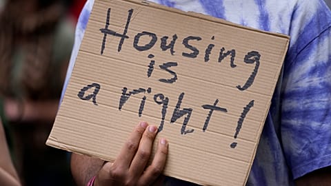 A protestor carries a poster, during a demonstration to demand solutions for Portugal's housing crisis, in Lisbon, Saturday, April 1, 2023.