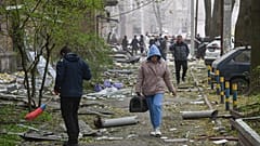 Eine Frau geht in einem Hof eines Wohnhauses spazieren, das durch einen russischen Angriff auf Dnipro (Ukraine) beschädigt wurde, Samstag, 25. April 2026.