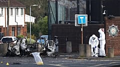 Kriminaltechniker untersuchen die Überreste einer Autobombe, die vor der Polizeistation Dunmurry in South Belfast explodiert ist, Sonntag, 26. April 2026. (AP Photo/Peter Morrison