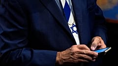 عضو في الكونغرس يتفقد هاتفه عقب خطاب بنيامين نتنياهو أمام جلسة مشتركة في مبنى الكابيتول بواشنطن