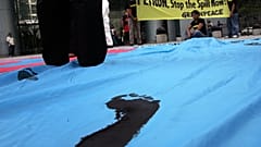 Greenpeace-Aktivisten hinterlassen Ölabdrücke auf einem riesigen Banner mit dem nachgeahmten Logo des Ölkonzerns Petron während eines stillen Protests.