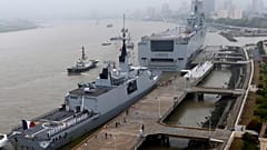 Dixmude, im Hintergrund das dritte französische amphibische Sturmschiff der Mistral-Klasse, und die französische Tarnkappenfregatte Aconit in der Militärwerft in Shanghai, 2015