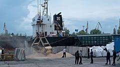 An excavator loads grain into a cargo ship at a grain port in Izmail, 26 April, 2023