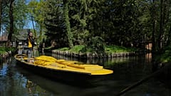 Postbotin Andrea Bunar steht auf einem Boot und steuert mit einem langen Ruder durch enge Wasserwege bei ihrer ersten Sommerpostrunde in Lehde, Lübbenau, am 29. April 2026.