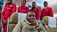 Sabastian Sawe posiert auf dem Flug von London mit Flugbegleiterinnen. Am neunundzwanzigsten April 2026 landet er am Jomo Kenyatta Airport in Nairobi, Marathon-Weltrekordler.