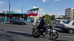 FILE: A man rides his motorbike that is adorned with an Iranian national flag, in southern Tehran, 21 April 2026