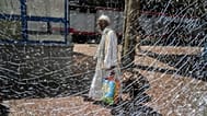 FILE: A Sudanese refugee is seen through a broken window as he prepares to enter his train to Aswan at Cairo's Ramses railway station, 21 July 2025
